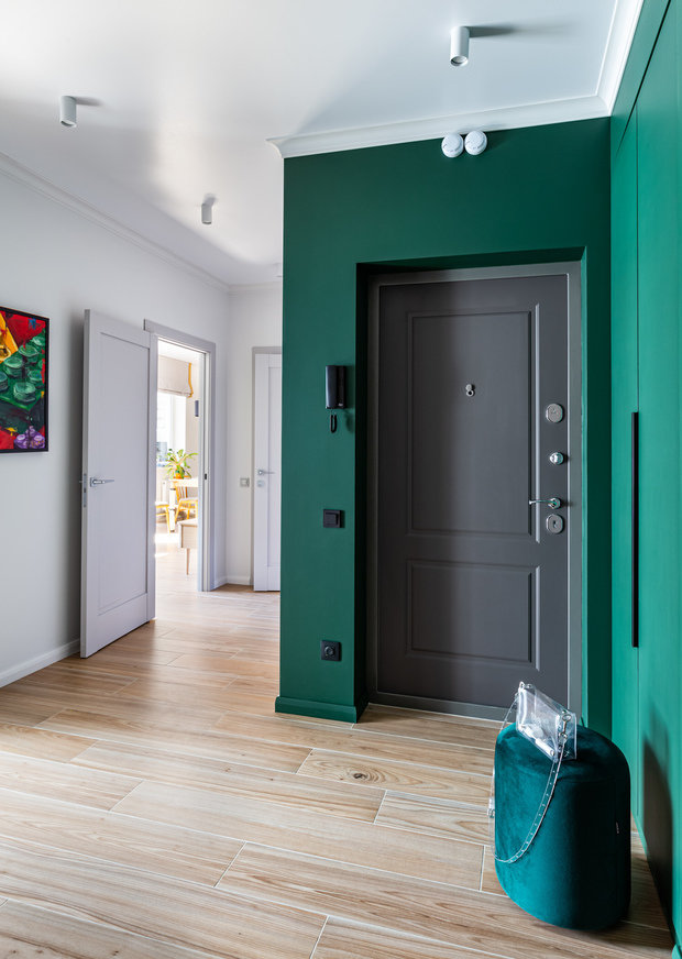 В прихожей керамогранит на полу и краска на стенах — довольно стандартное решение. Здесь основную роль играет насыщенный зеленый цвет во входной зоне.