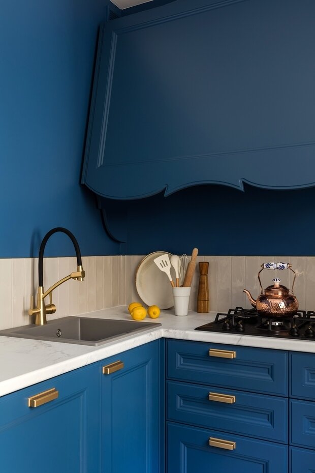 Синюю кухню не хотелось загромождать фартуком, вертикально расположенная плитка с латунным профилем по периметру задает легкий ритм.