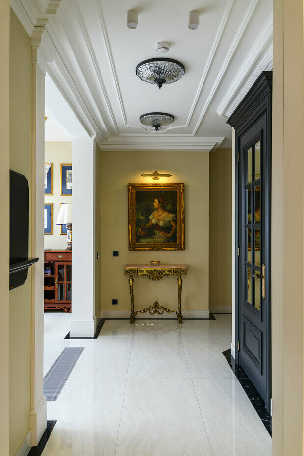 Напротив входной двери располагается антикварная консоль из настоящей литой бронзы и мрамора. Над ней — подлинная картина испанского художника.