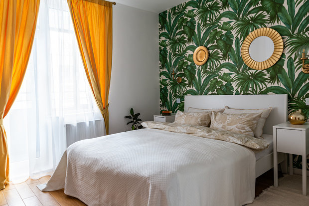 В спальне для создания уюта на одну из стен было решено добавить обои с современным растительным принтом. 