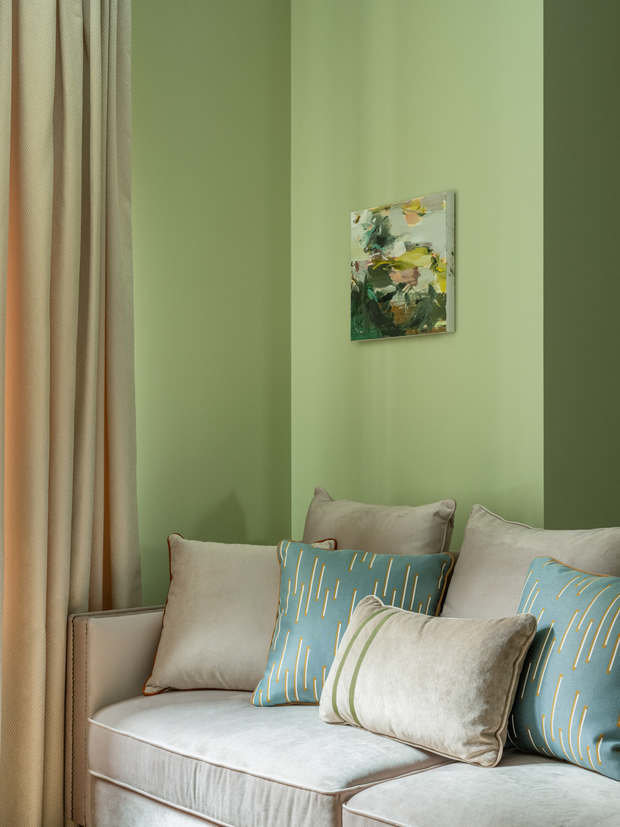 Для отделки стен гостиной выбрали английский зеленый в сочетании со светлыми вставками внутри молдингов. На полу паркетная доска натурального светлого оттенка дуба, который гармонично дополняет зеленый оттенок стен, а также оттеняет яркие терракотовые акценты.
